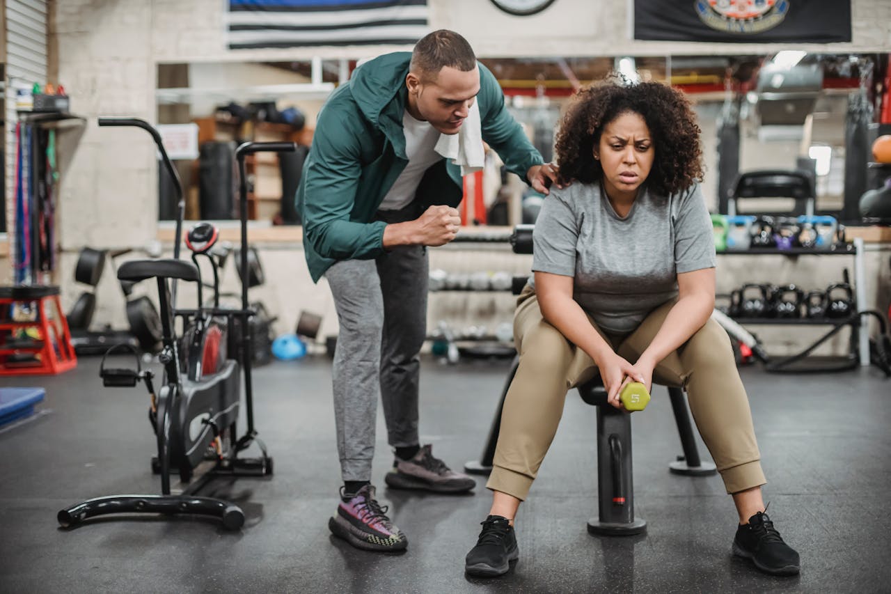 A personal trainer motivates a woman during her fitness workout session in a gym.